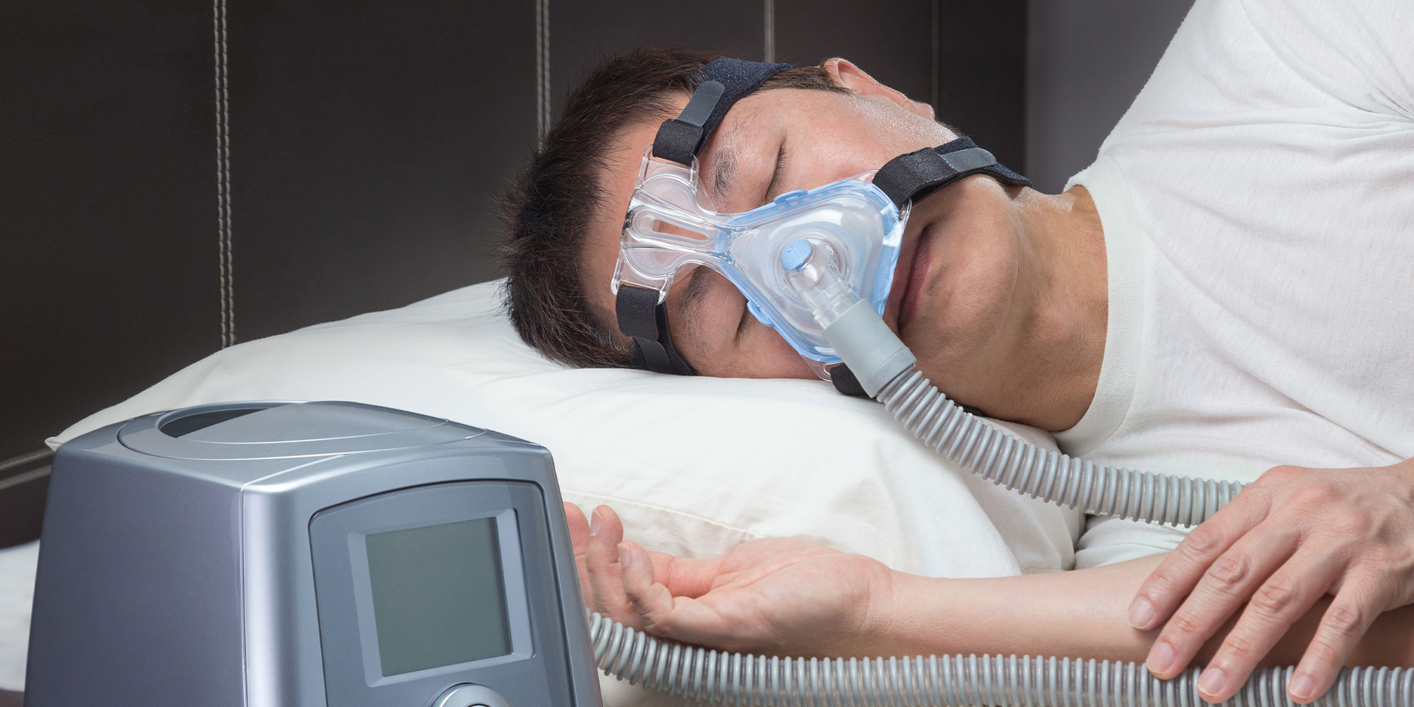 person sleeping and using sleeping mask to help breath