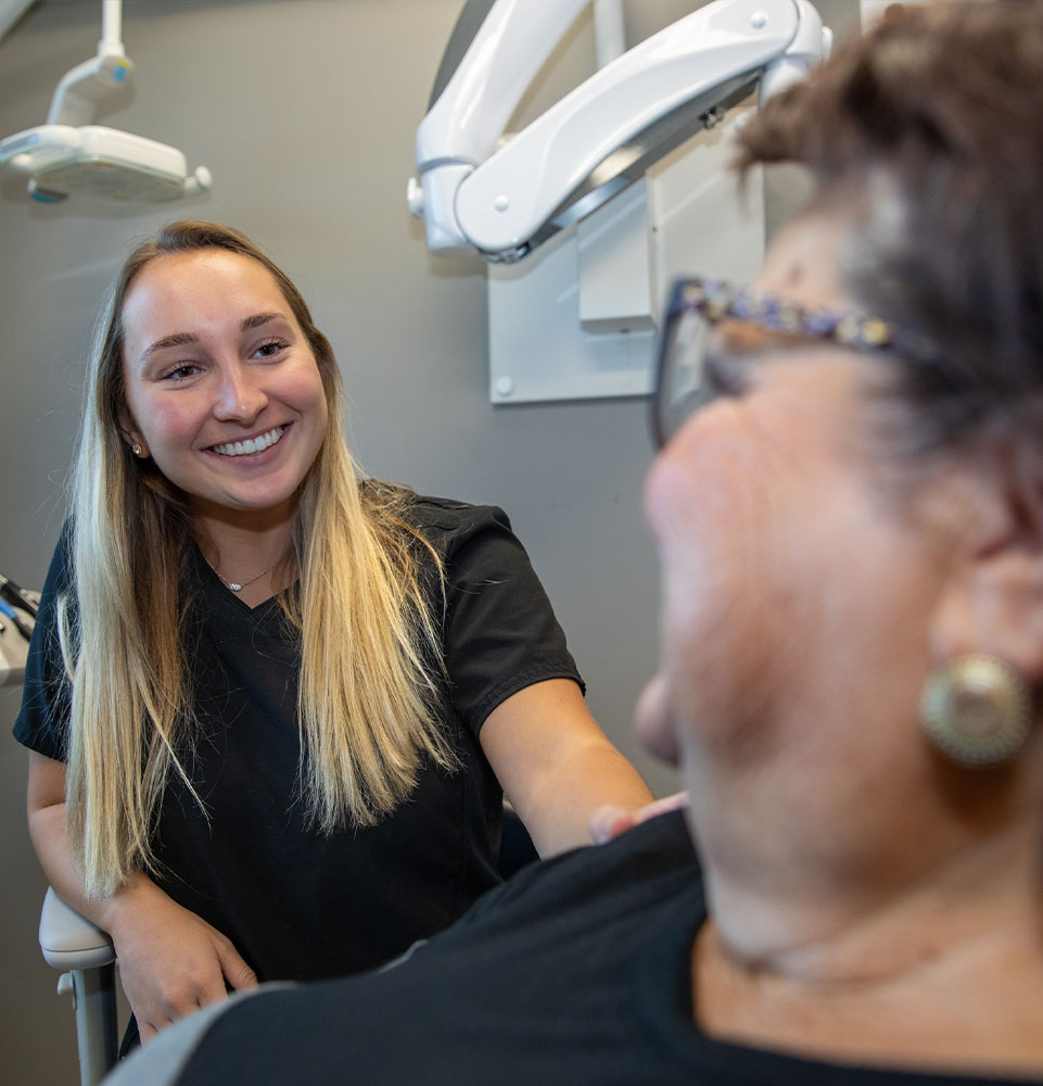 doctor helping patient within the dental treatment center with implant model