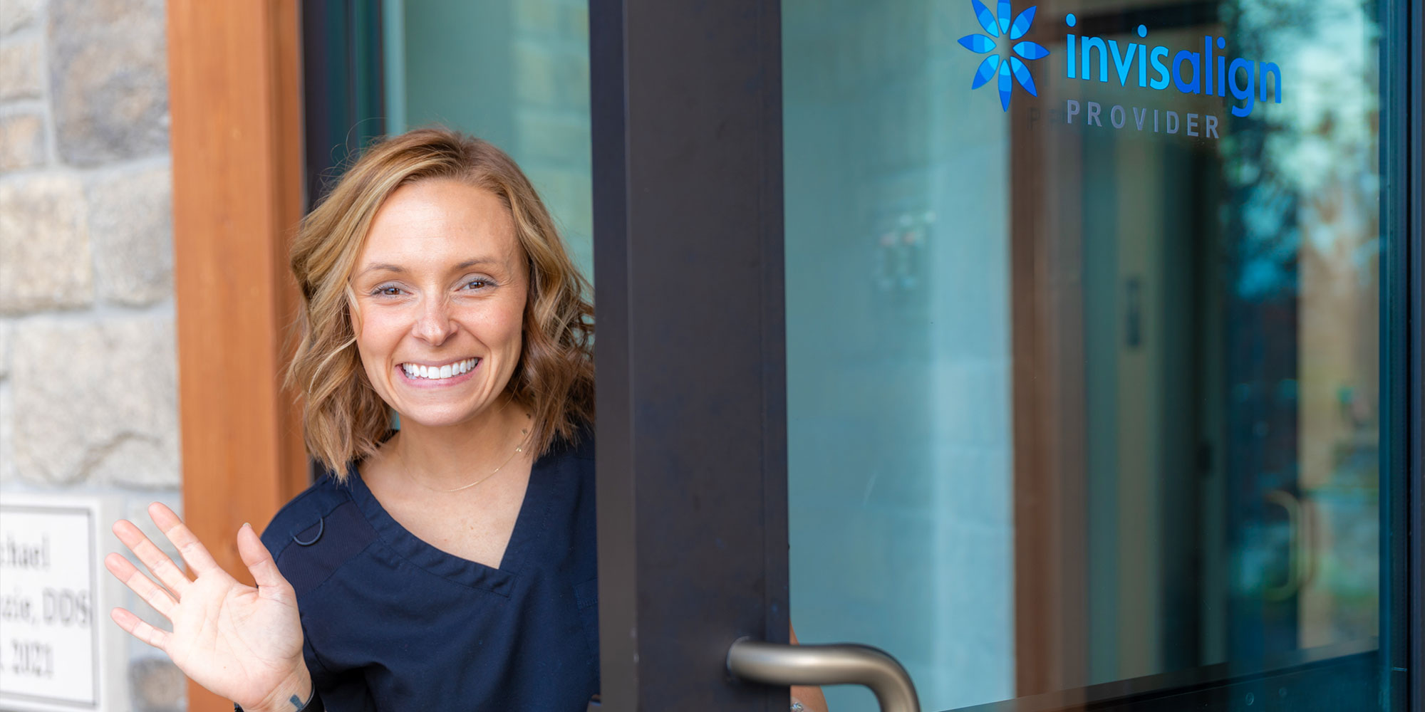 staff member at the front door of the dental center smiling brightly
