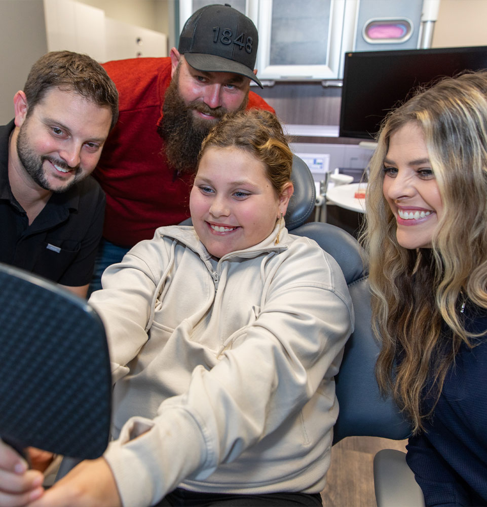 patient smiling brightly with doctor and staff member within the dental center