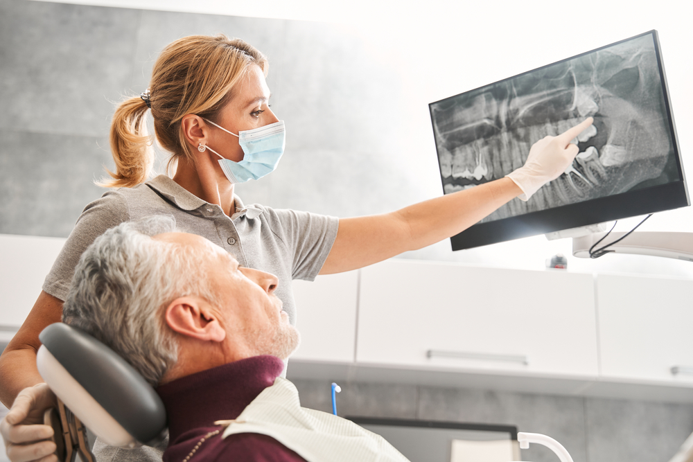 An animated graphic depicting a dentist using a robotic arm to precisely place a dental implant into a patient's jaw. Focus on technology and precision in a dental setting. No text on the image.